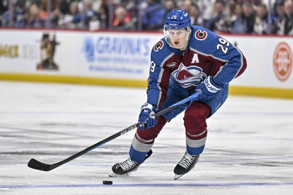 Натан Маккиннон в столкновении с вратарём Коннором Ингрэмом во время матча НХЛ между Колорадо Эвеланш и Эдмонтон Ойлерз.